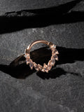 BVLA Rose gold ring with clear gemstones on a dark textured surface