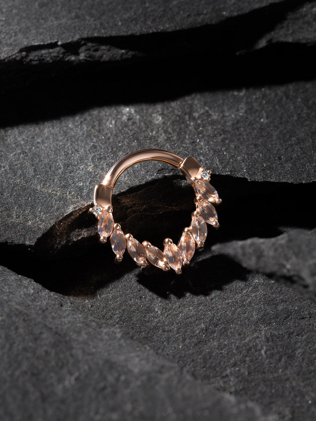 BVLA Rose gold ring with clear gemstones on a dark textured surface