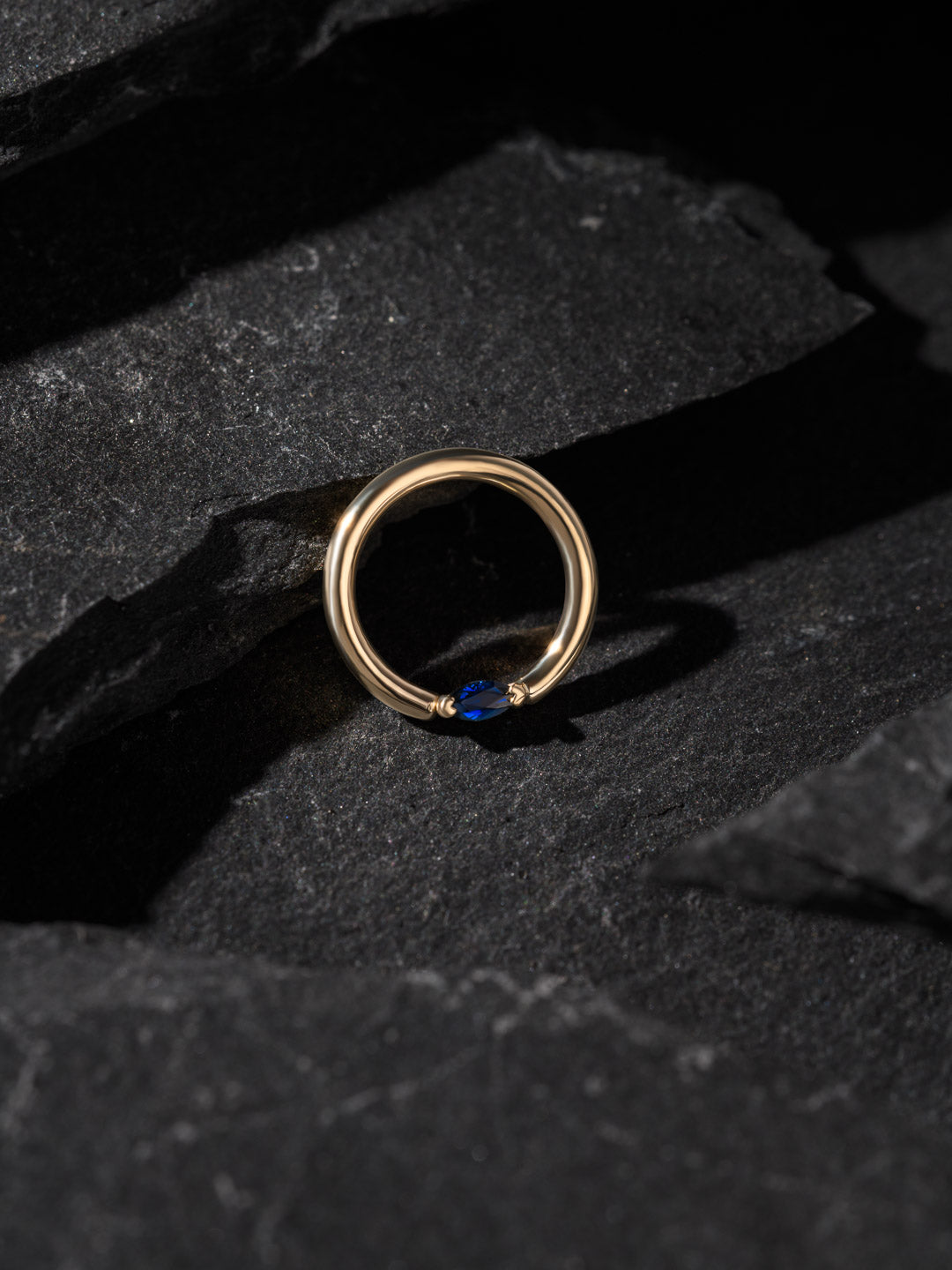 BVLA Gold ring with a blue gemstone on a dark stone surface