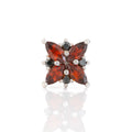 Star-shaped earring with red and black gemstones on a white background