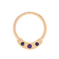 Gold ring with three purple gemstones on a white background