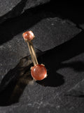 Gold barbell with peach-colored beads on a dark stone surface
